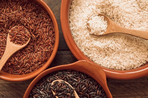 Overhead view organic rice grains with wooden spoon
