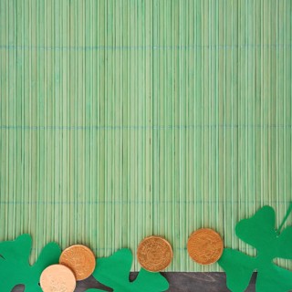 Paper clovers near coins bamboo mat