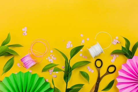 Paper flower confetti green leaves thread spool yellow background