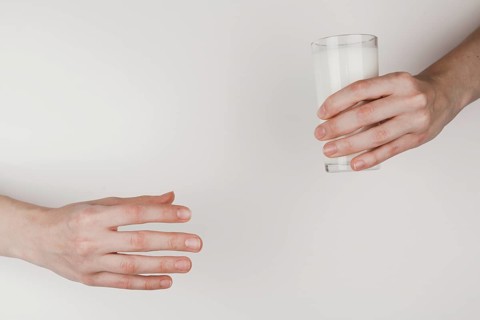 Person handing glass milk another one