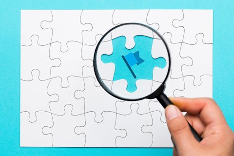 Person s hand holding magnifying glass flag icon blue backdrop