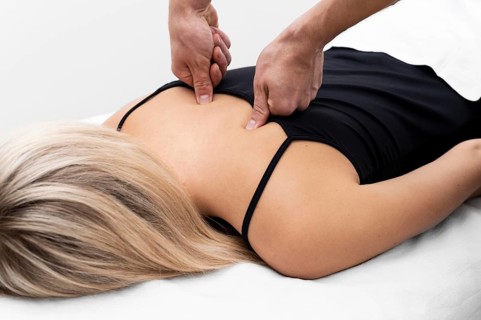 Physiotherapist performing back massage female patient
