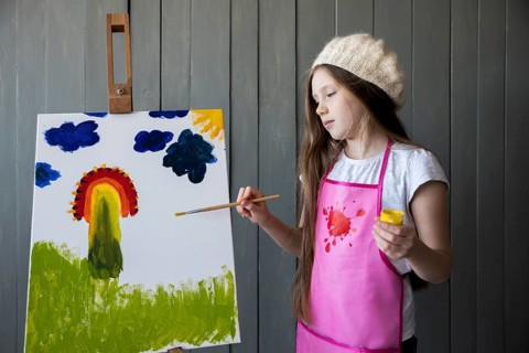 Portrait cute girl painting easel with paintbrush