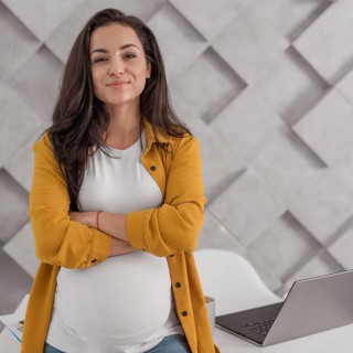 Pregnant woman posing with laptop home