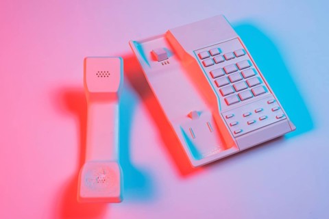 Receiver landline telephone pink background with blue shadow