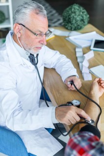 Serious doctor measuring blood pressure patient