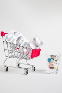 Shopping cart with pill blister medicines glass white background