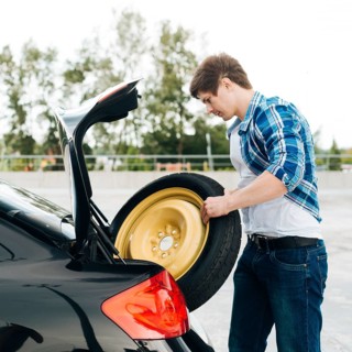 Side view man taking out spare tire