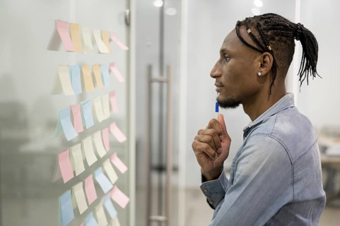 Side view man thinking office while looking sticky notes