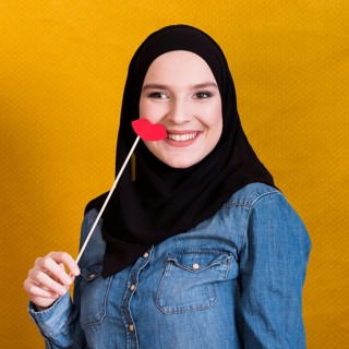Smiling muslim woman holding paper prop shape red lips backdrop