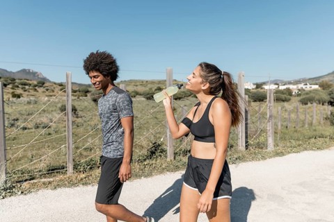 Smiling people walking while woman drinking water