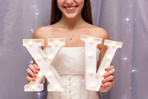 Teenage girl celebrating quinceanera while holding roman numerals
