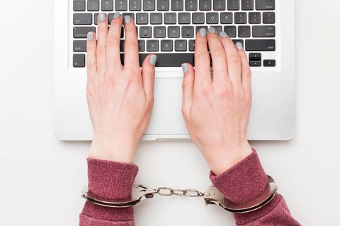 Top view hands with handcuffs working laptop