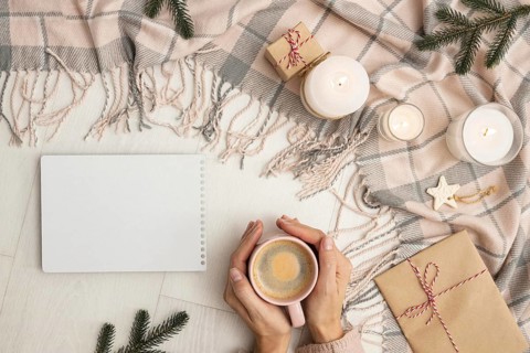 Top view person holding mug with blanket candles