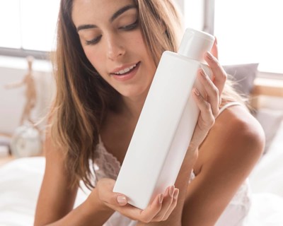 Woman holding body lotion self care home
