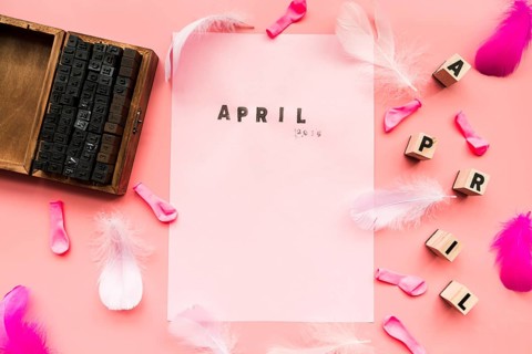 Wooden typographic blocks balloons feather april blocks april stamp white paper against pink backdrop