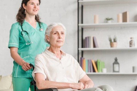 Young nurse assisting disabled senior woman sitting wheel chair