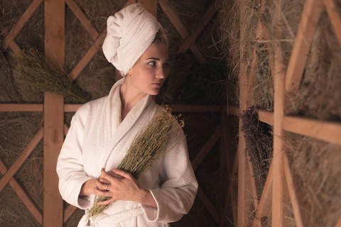 Young woman bathrobe holding medical herbs