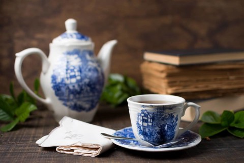 Antique porcelain tea cup teapot with books folded napkin wooden table