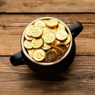 Cauldron with gold coins wooden background