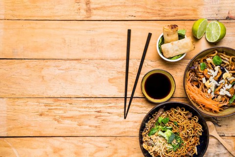 Chopsticks with spring rolls noodles sauces with chopsticks wooden table