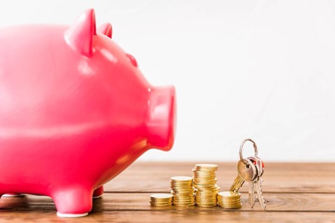 Close up pink piggybank near stacked coins key