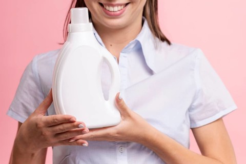 Close up smiley woman holding detergent bottle