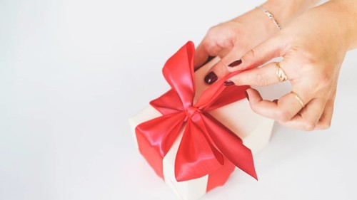 Close up woman s hand unwrapping gift box white background