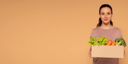 Copy space woman holding cartoon box with vegetables