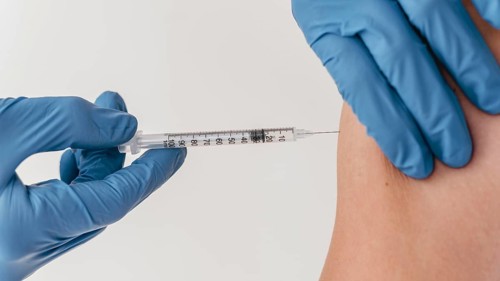 Doctor with gloves administering vaccine patient