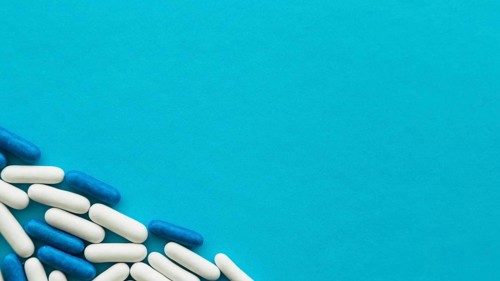Elevated view white blue candy capsules corner cyan backdrop