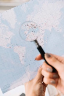 Female tourist searching places travel map through magnifying glass