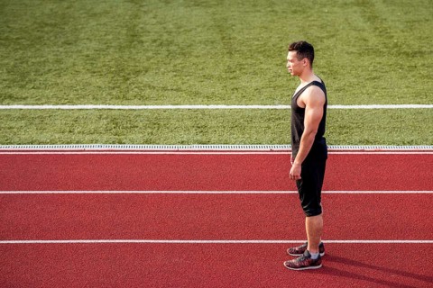 Fitness young male runner standing red running track