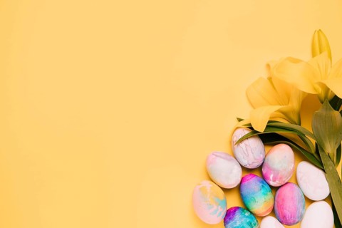 Fresh lily flowers with colorful easter eggs corner yellow background