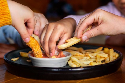 Hands holding french fries close up