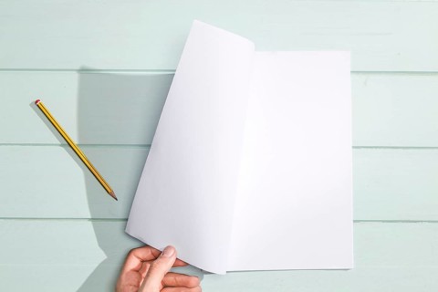 Hand turning white page flat lay