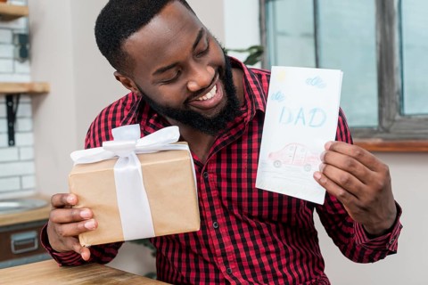 Happy black man holding greeting card gift