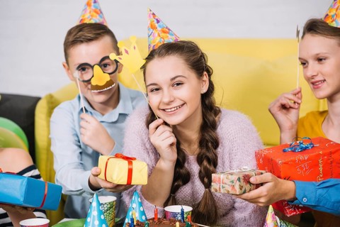 Happy friends holding props hand giving gifts smiling teenage girl