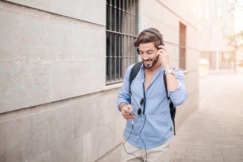Happy man walking pavement listening music
