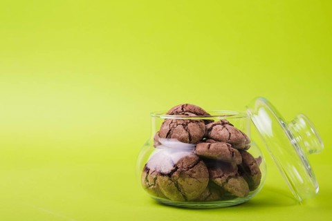 Homemade baked chocolate cookies glass jar green background