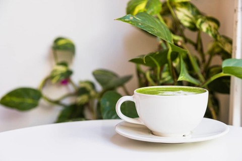 Hot matcha green tea cup saucer white table