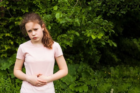 Innocent girl holding her stomach while having stomach pain park