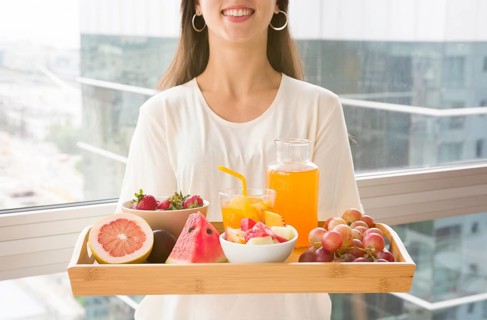 Midsection woman holding wooden tray with many fruits juice
