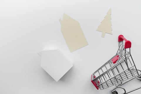 Paper cut out house christmas tree with miniature house model shopping cart isolated white background