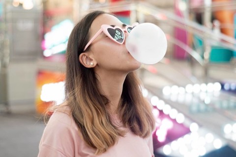 Portrait young girl blowing bubble gum