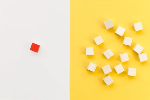 Red cube separated from group wooden ones