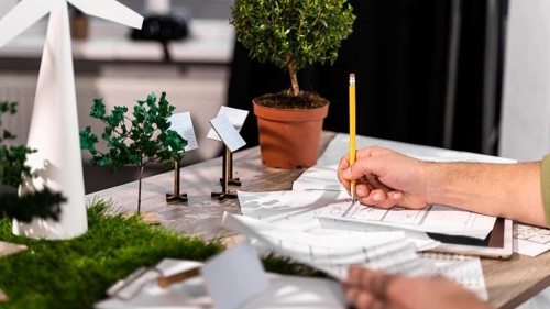 Side view man working eco friendly wind power project with paper plans