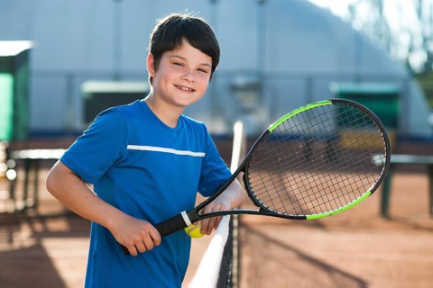 Smiley kid resting tennis net