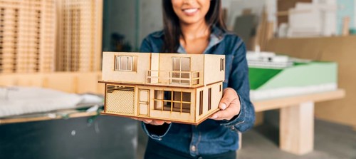 Smiling african american woman showing model house