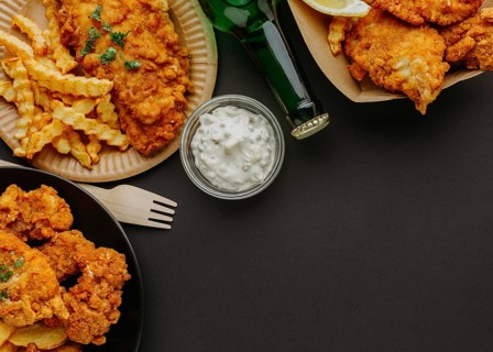 Top view fish chips plates with cutlery beer bottle